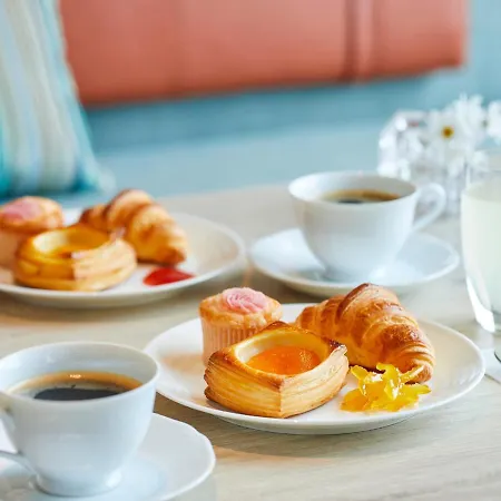 Grand Nikko Tokyo Bay Maihama Hotel Urayasu Exterior photo The photo features a breakfast or brunch setup with several plates and beverages. On the table, there are two plates with a variety of pastries, including items that look like croissants and sweet pastries topped with colorful icing. There are also s